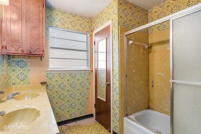 bathroom with bath / shower combo with glass door, vanity, and a textured ceiling