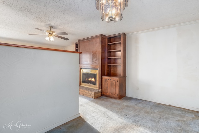 unfurnished living room with ceiling fan with notable chandelier, a textured ceiling, carpet flooring, and a fireplace