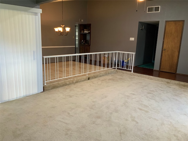 unfurnished room with carpet, a towering ceiling, and a chandelier