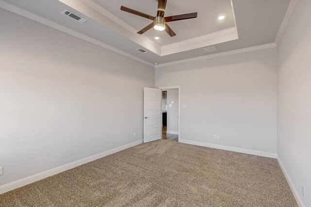 carpeted spare room with ornamental molding, a tray ceiling, and ceiling fan