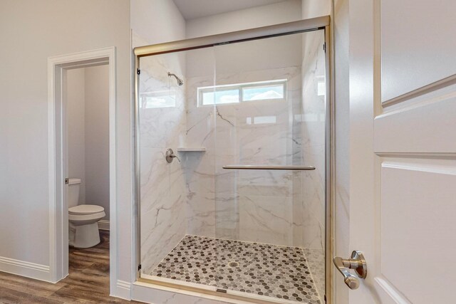 bathroom with wood-type flooring, toilet, and an enclosed shower