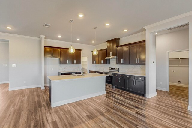 kitchen featuring stainless steel electric stove, a center island with sink, backsplash, and dark wood-type flooring