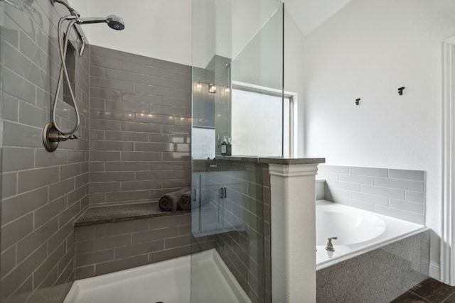 bathroom featuring shower with separate bathtub, lofted ceiling, and tile patterned floors