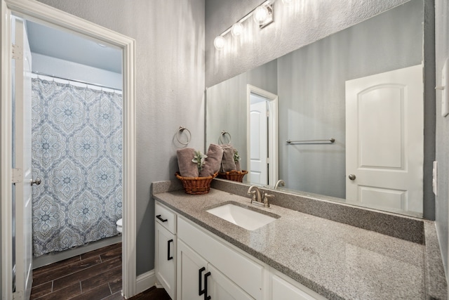 bathroom with a shower with curtain, hardwood / wood-style flooring, vanity, and toilet