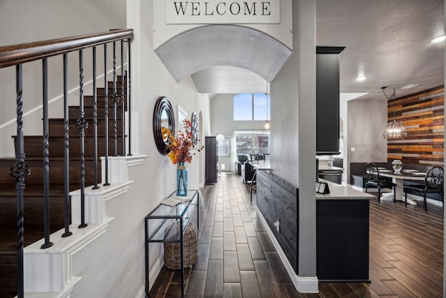 interior space featuring a textured ceiling, wooden walls, light stone counters, and dark hardwood / wood-style flooring