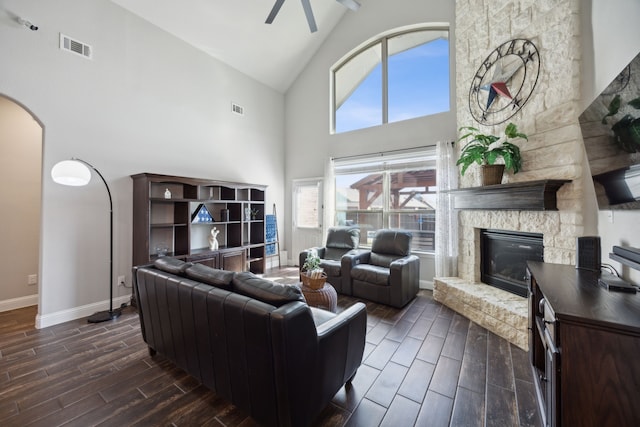 living room with a fireplace, high vaulted ceiling, ceiling fan, and dark wood-type flooring