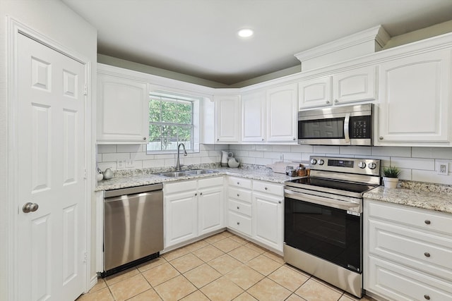 kitchen featuring light tile patterned floors, sink, backsplash, white cabinetry, and appliances with stainless steel finishes