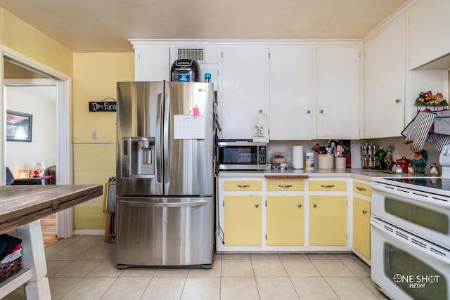 kitchen with white cabinets, light tile patterned flooring, and appliances with stainless steel finishes