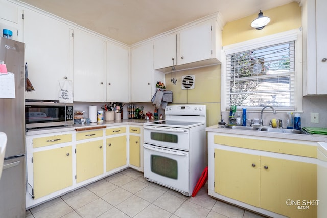 kitchen with stainless steel appliances, white cabinets, light tile patterned flooring, and sink