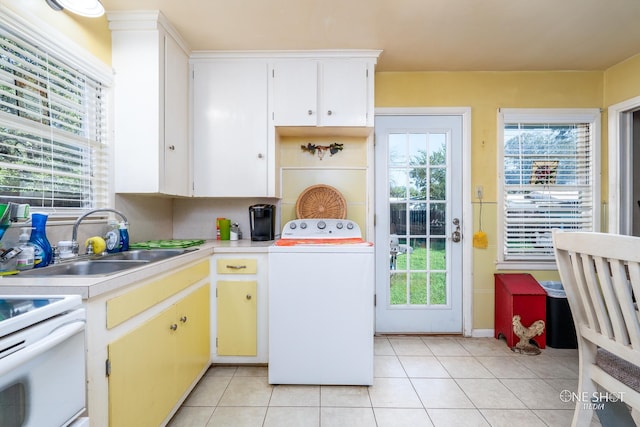 kitchen with light tile patterned floors, white cabinetry, sink, and washer / dryer