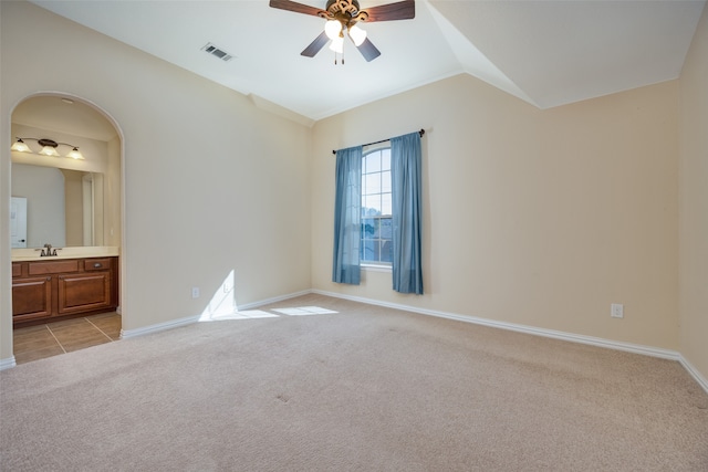 empty room with lofted ceiling, sink, light carpet, and ceiling fan