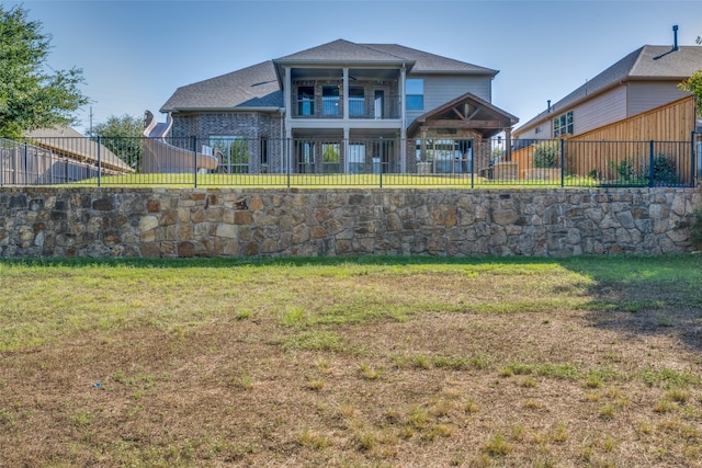 back of house with a balcony and a yard