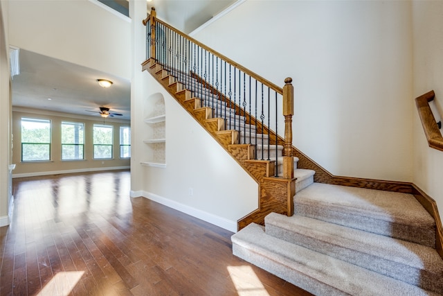 stairway with wood-type flooring, ceiling fan, and a high ceiling