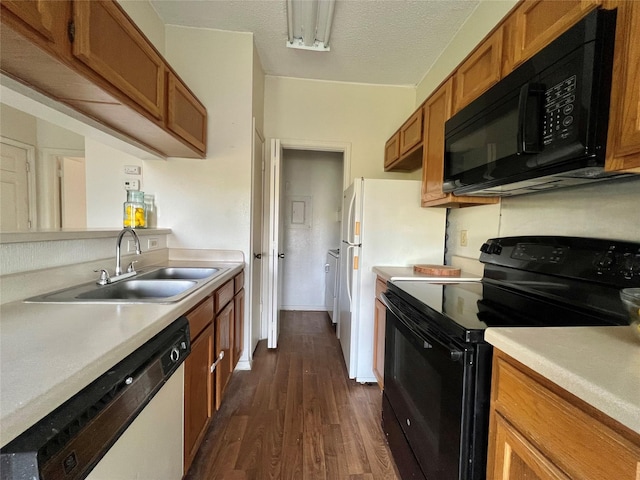 kitchen featuring brown cabinets, dark wood-style flooring, light countertops, black appliances, and a sink