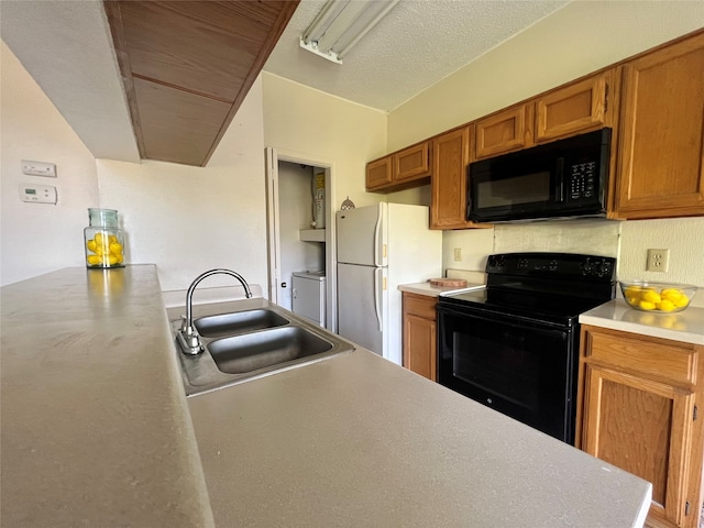 kitchen with sink, black appliances, kitchen peninsula, and washing machine and clothes dryer