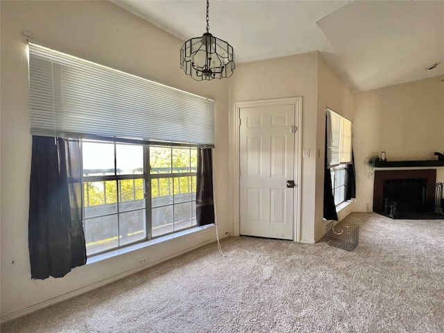 unfurnished living room featuring carpet floors, a wealth of natural light, and a chandelier