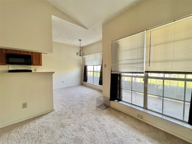 interior space with lofted ceiling, a wealth of natural light, and light colored carpet