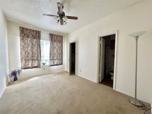 unfurnished bedroom with ensuite bath, a textured ceiling, ceiling fan, and carpet flooring