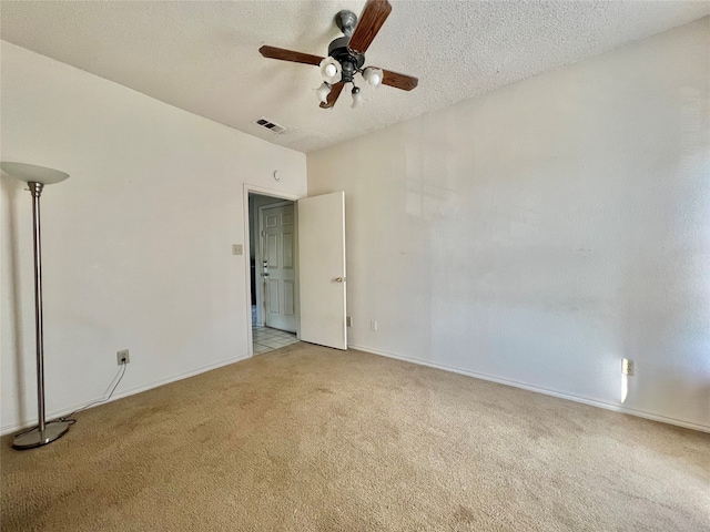 spare room with ceiling fan, light colored carpet, and a textured ceiling