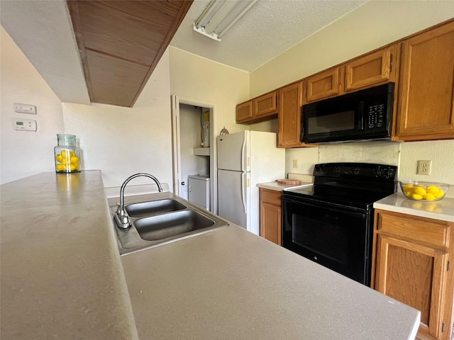 kitchen with brown cabinets, washing machine and clothes dryer, light countertops, black appliances, and a sink