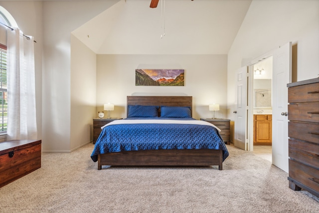 carpeted bedroom with ensuite bath, ceiling fan, and high vaulted ceiling