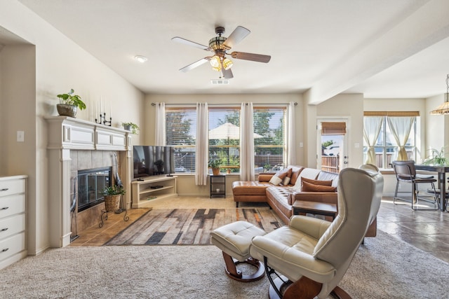 living room featuring carpet floors, ceiling fan, and a tiled fireplace