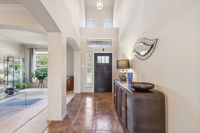 entrance foyer featuring a high ceiling, dark tile patterned flooring, and ornamental molding