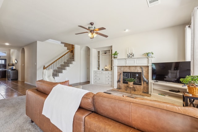 tiled living room with a tile fireplace and ceiling fan