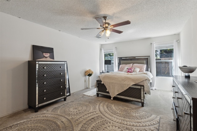 carpeted bedroom with multiple windows, a textured ceiling, and ceiling fan