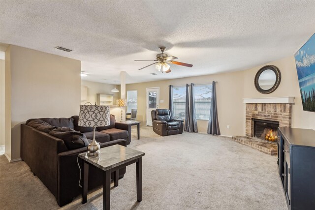 living room featuring ceiling fan, a brick fireplace, light carpet, and a textured ceiling