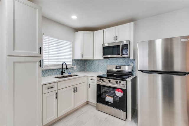 kitchen with white cabinets, stainless steel appliances, a sink, and light countertops