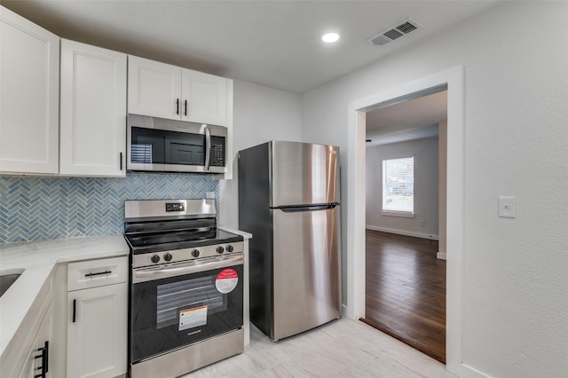 kitchen with white cabinetry, visible vents, light countertops, appliances with stainless steel finishes, and decorative backsplash