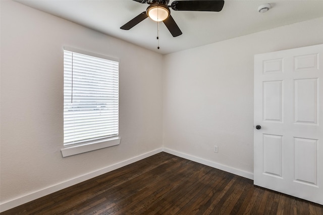 unfurnished room with dark wood-style floors, a ceiling fan, and baseboards