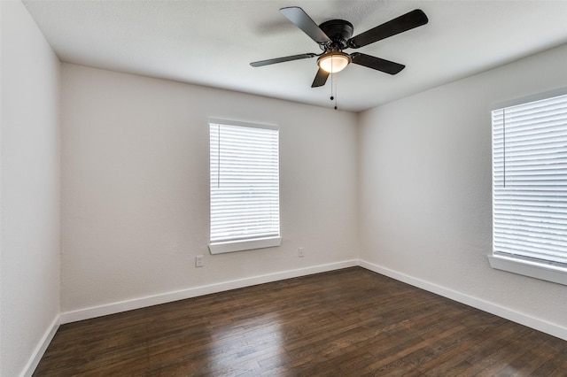 spare room with ceiling fan, baseboards, and dark wood finished floors