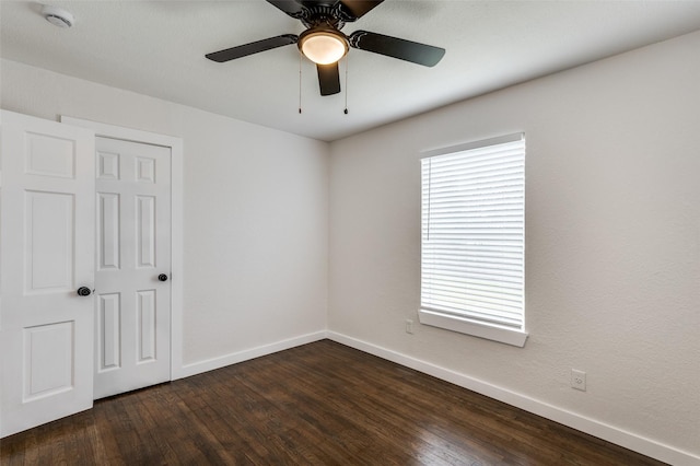 spare room with dark wood-style floors, baseboards, and a ceiling fan