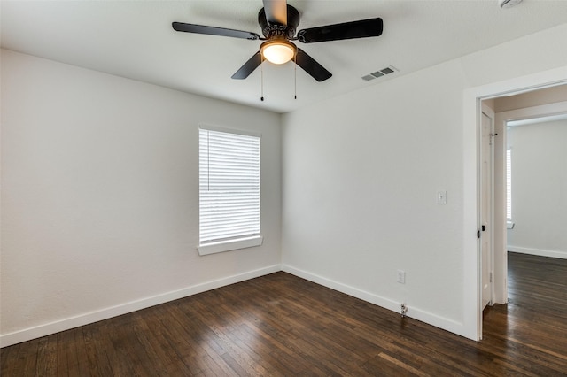 unfurnished room with a ceiling fan, dark wood finished floors, visible vents, and baseboards