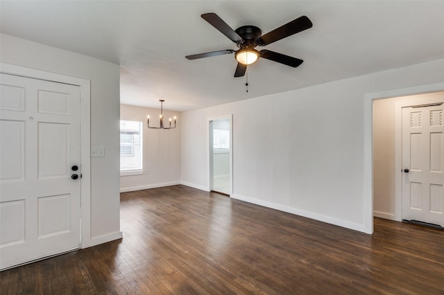 unfurnished room featuring baseboards, dark wood finished floors, and ceiling fan with notable chandelier