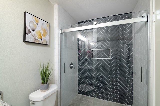 bathroom featuring a shower with shower door and toilet