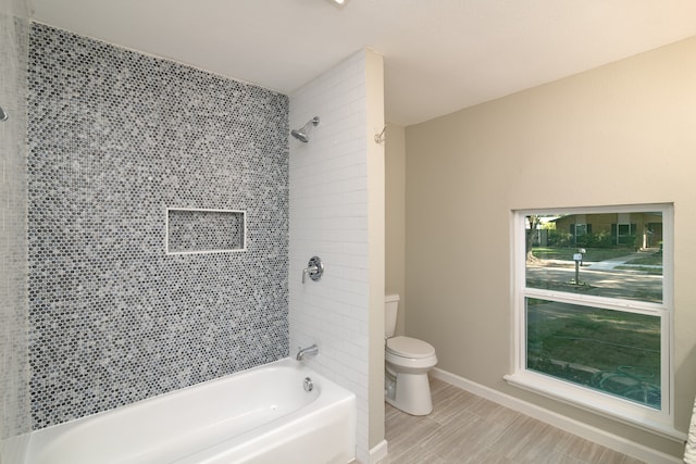 bathroom featuring tiled shower / bath and toilet