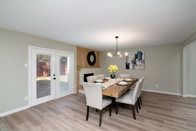 dining room with a brick fireplace, light wood-type flooring, and a chandelier