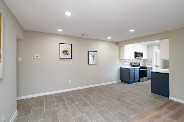 kitchen featuring light hardwood / wood-style floors, white cabinets, decorative backsplash, stainless steel appliances, and blue cabinetry