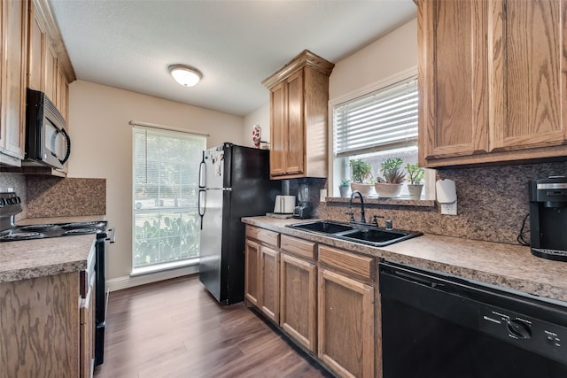 kitchen with black appliances, decorative backsplash, hardwood / wood-style floors, and sink