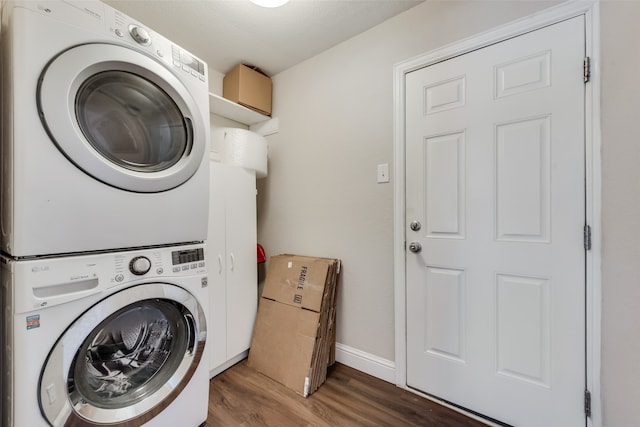 washroom featuring stacked washer / drying machine and dark hardwood / wood-style floors