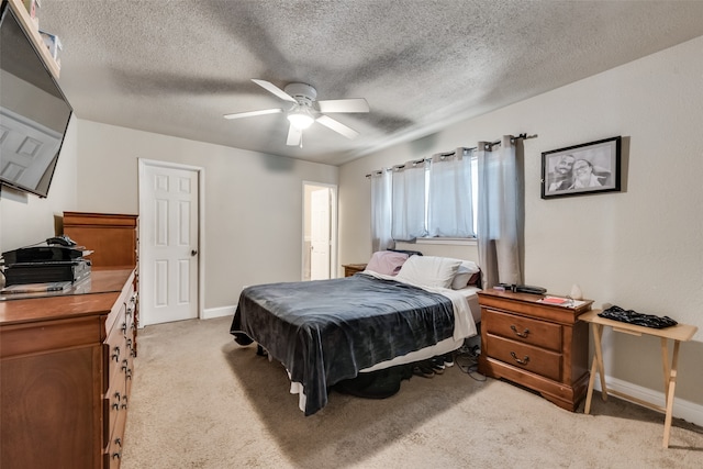 bedroom featuring a textured ceiling, light carpet, and ceiling fan