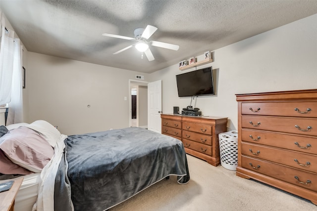 bedroom featuring a textured ceiling, ceiling fan, and light colored carpet