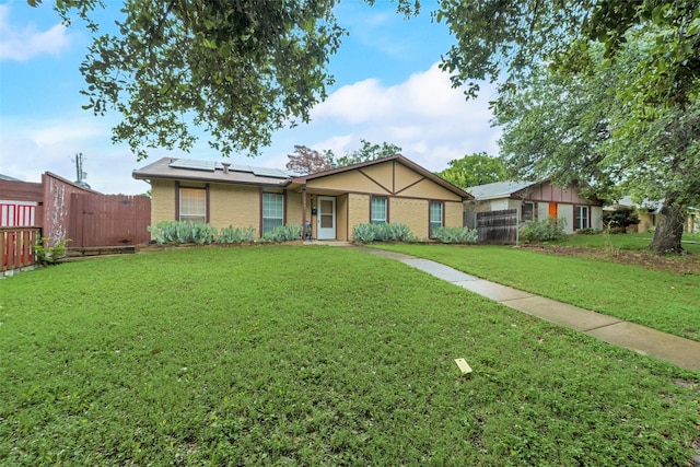 single story home with a front yard and solar panels