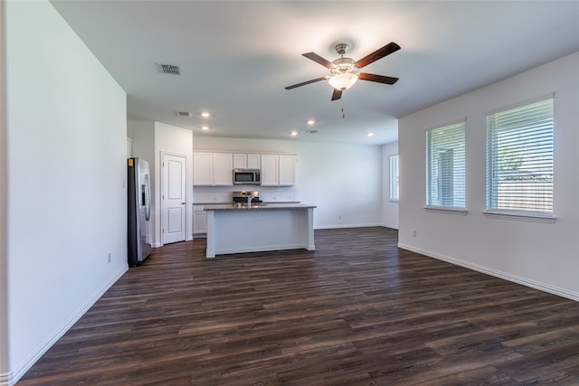 kitchen with dark wood-type flooring, white cabinets, stainless steel appliances, ceiling fan, and a center island with sink