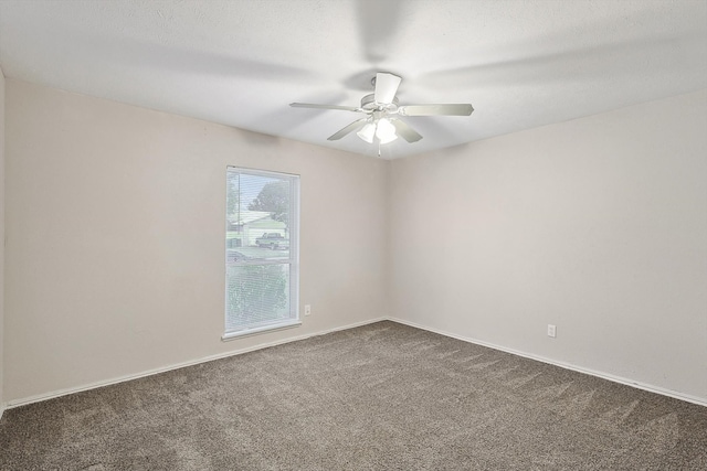 spare room featuring dark carpet and ceiling fan