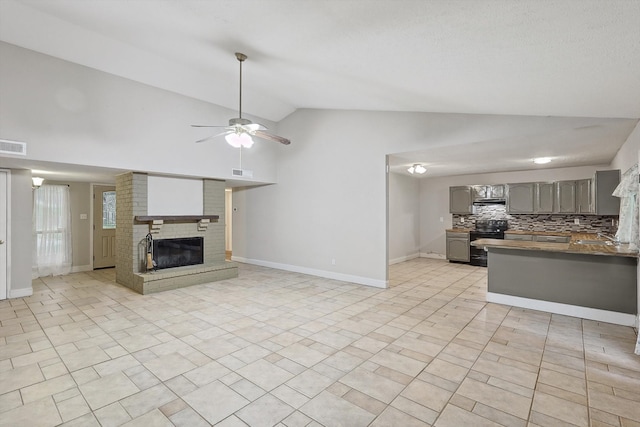 unfurnished living room with ceiling fan, light tile patterned flooring, sink, a brick fireplace, and high vaulted ceiling