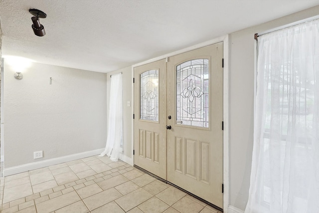 foyer entrance featuring a textured ceiling and light tile patterned floors